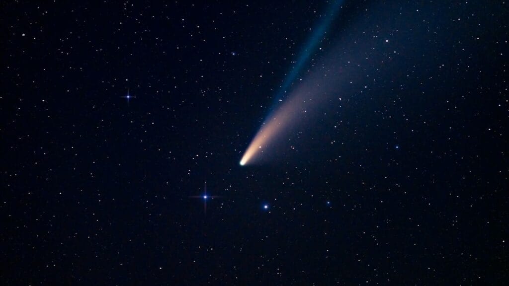 A comet with a glowing tail streaking across the night sky