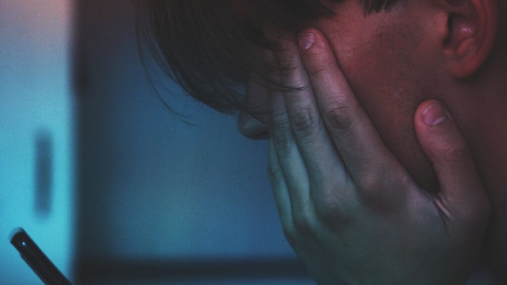 A person alone at night lit by a smartphone, representing AI companion chatbots and loneliness