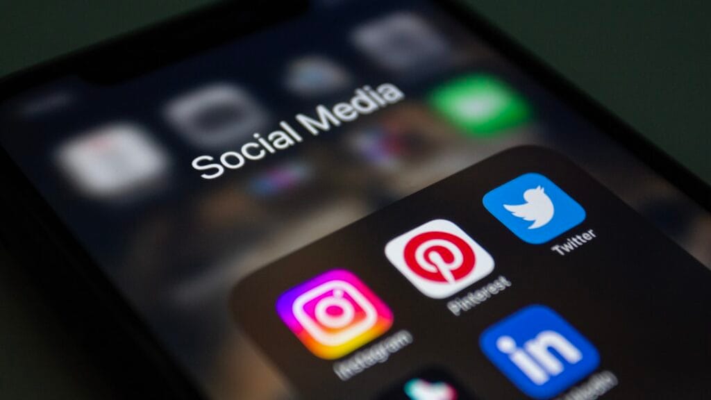 Person holding a smartphone in the dark showing social media apps