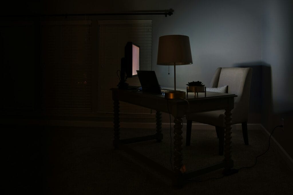 A laptop and desk lamp in a dark room at night