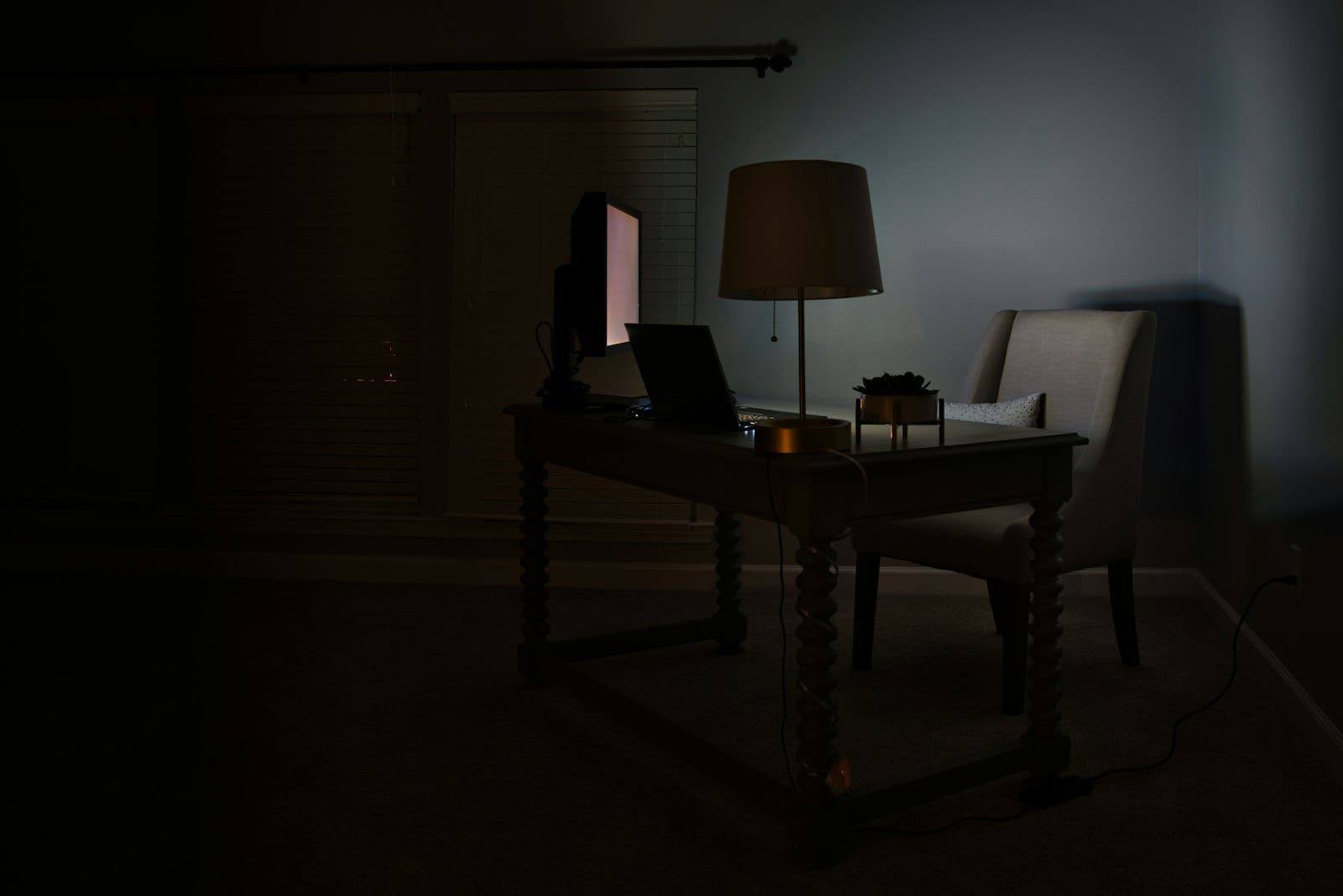 A laptop and desk lamp in a dark room at night
